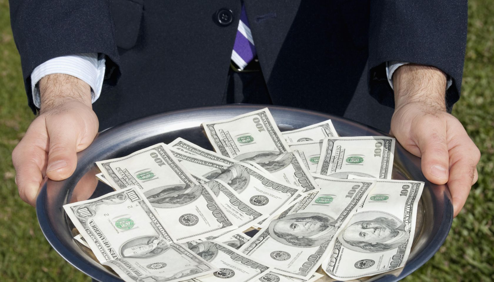 Businessman holding US currency notes on a plate
