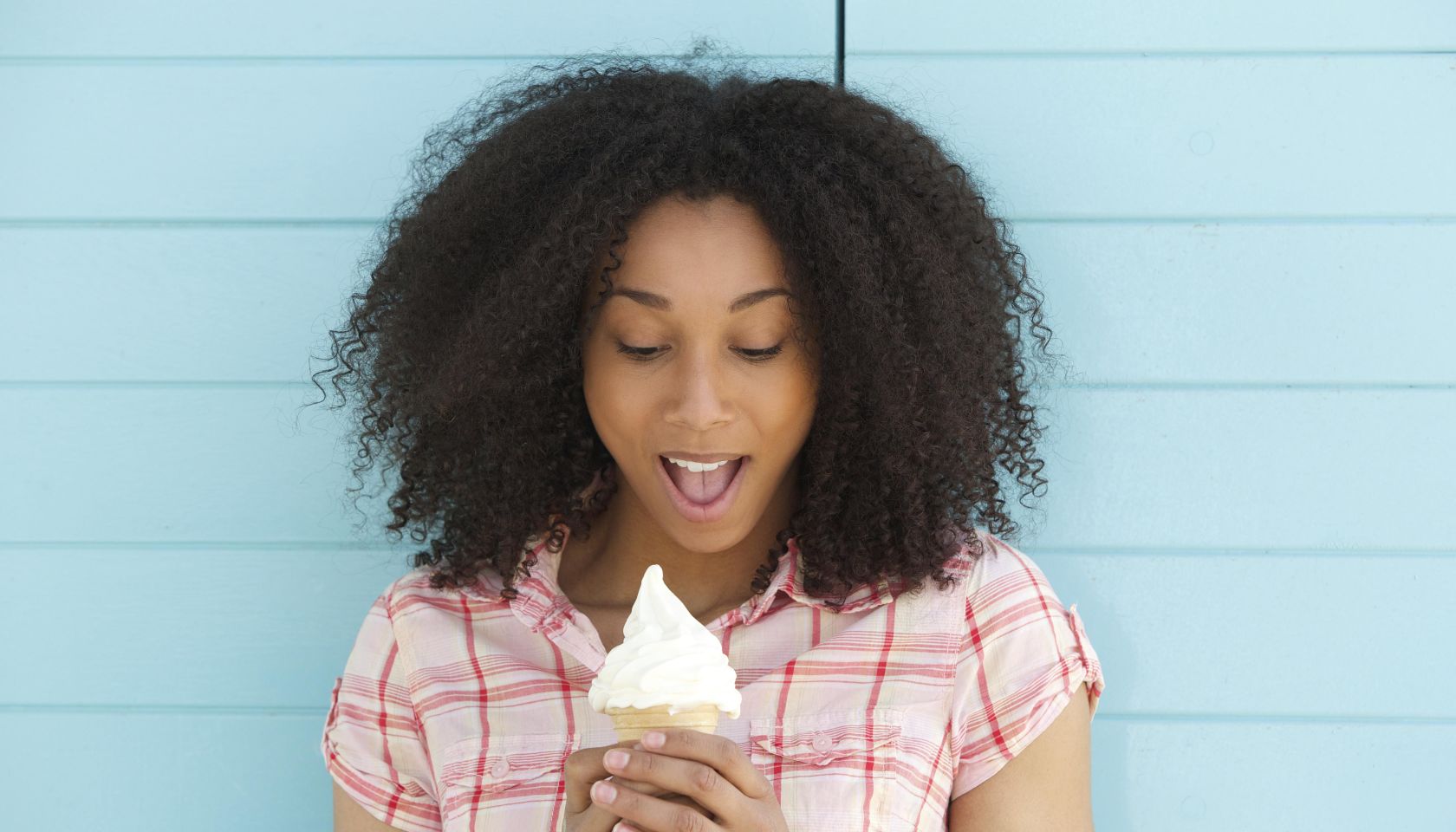 Close up portrait of a cute young woman looking surprised with ice cream outdoors