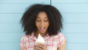 Close up portrait of a cute young woman looking surprised with ice cream outdoors