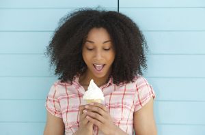 Close up portrait of a cute young woman looking surprised with ice cream outdoors