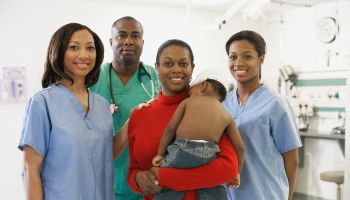 African American mother and baby surrounded by medical professionals