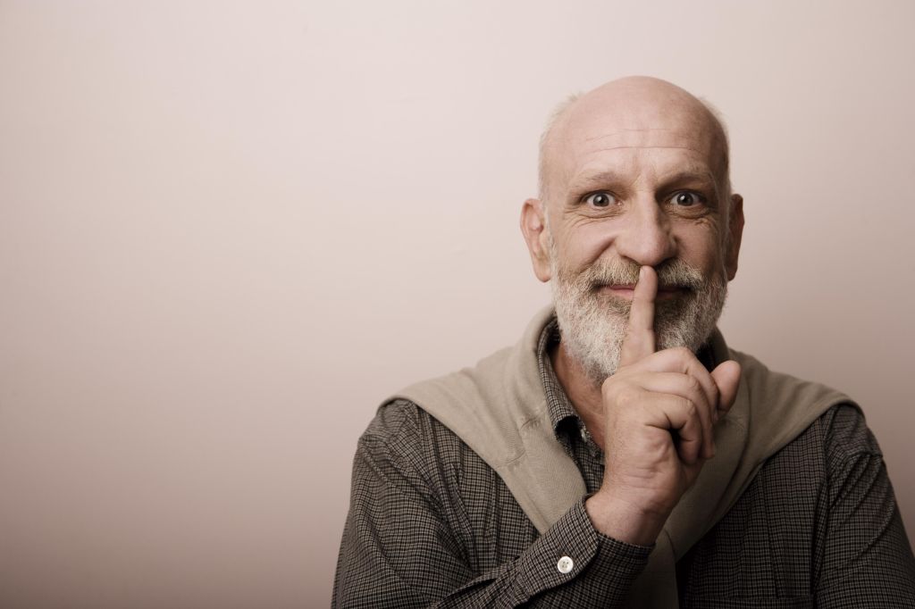 Studio portrait of mature man with finger on lips