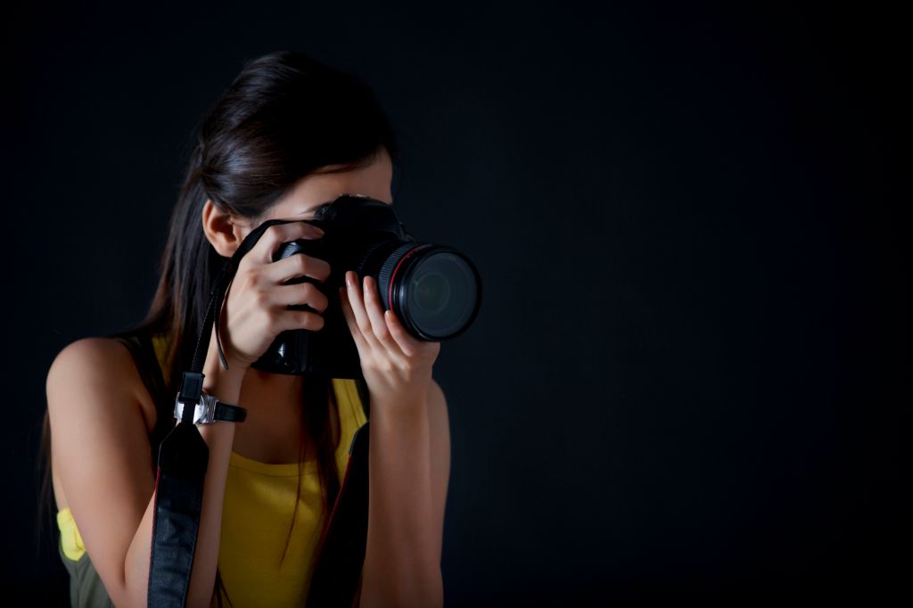 Close-up of young female photographer taking a photograph