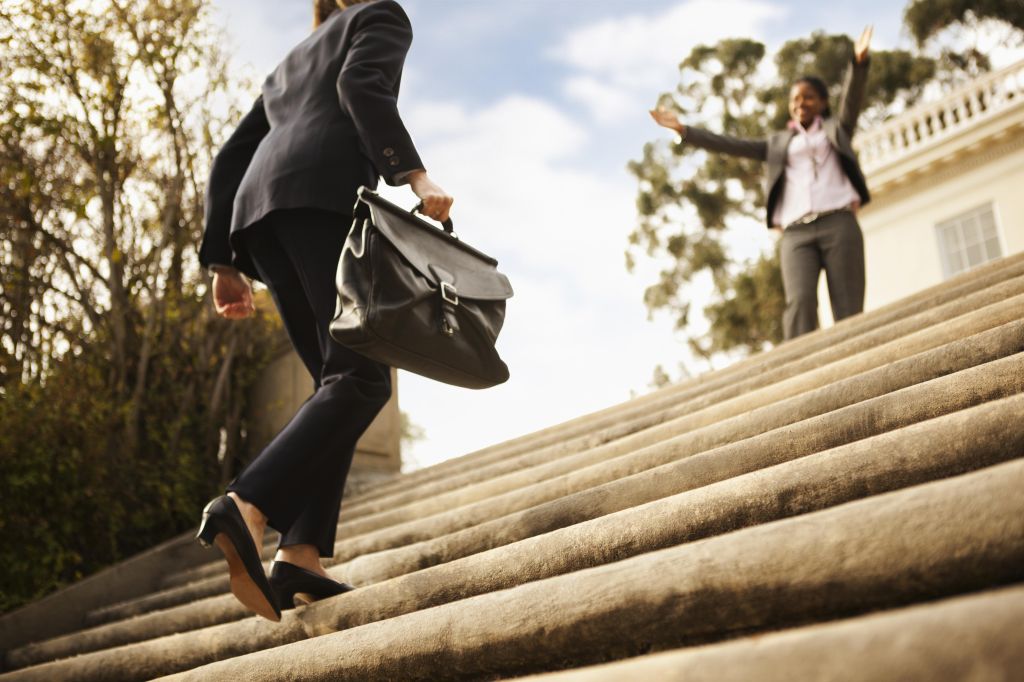 Businesswoman walking up stairs toward co-worker