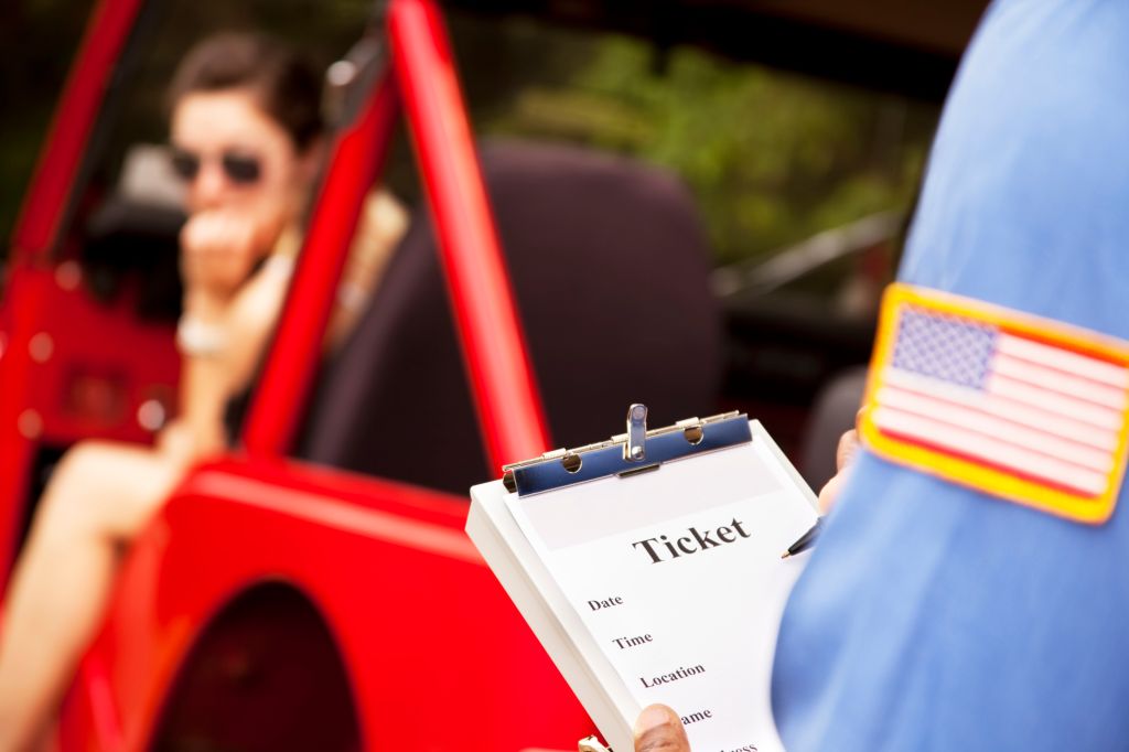 Caucasian female in red vehicle getting a ticket from policeman