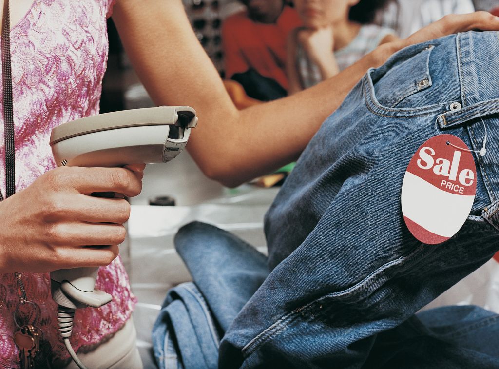 Close up of a Shop Assistant Scanning the Price Tag on a Pair of Jeans at the Checkout Counter of a Clothes Shop