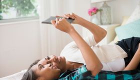Mother and daughter laying on bed using digital tablet
