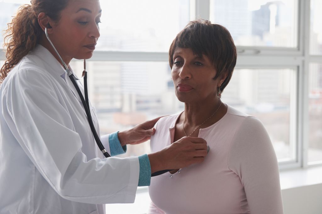 Doctor listening to heartbeat of patient near window