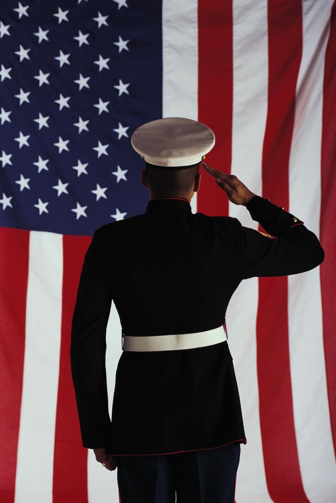 Man in U.S. Marine Corps uniform saluting American flag