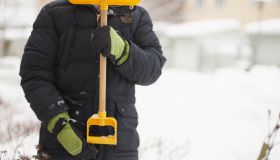 Child holding snow spade in front of face