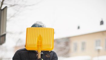 Child holding snow spade in front of face