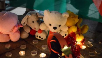 People leave assorted toys and candles in the memory of the...
