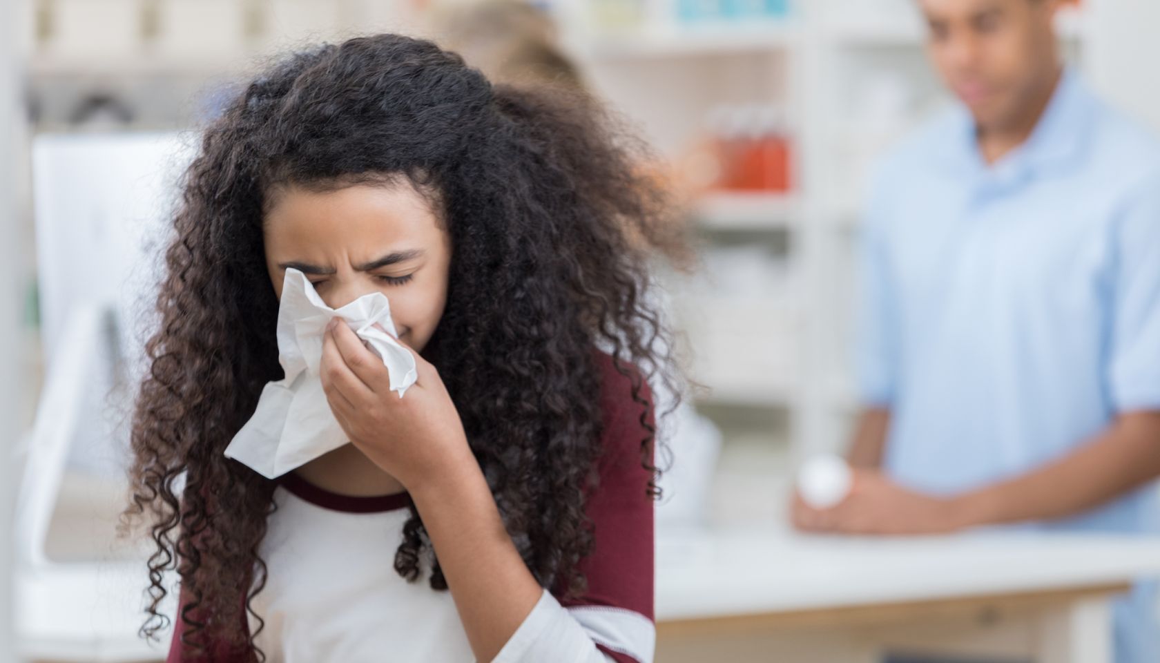 African American preteen girl uses tissue in pharmacy