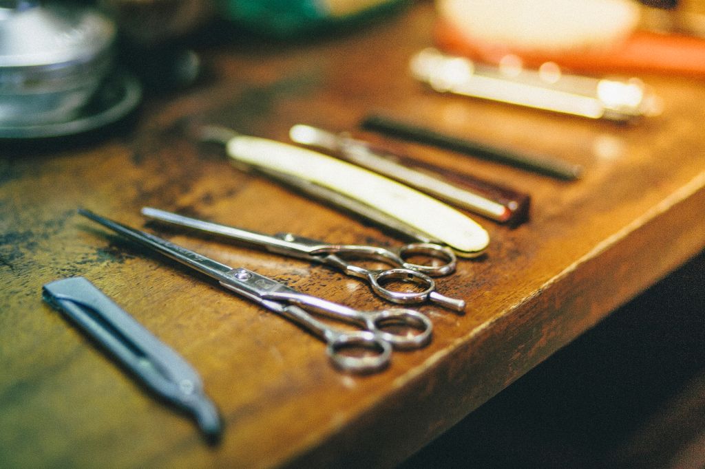 Barbers scissors and razors on wooden surface, close-up