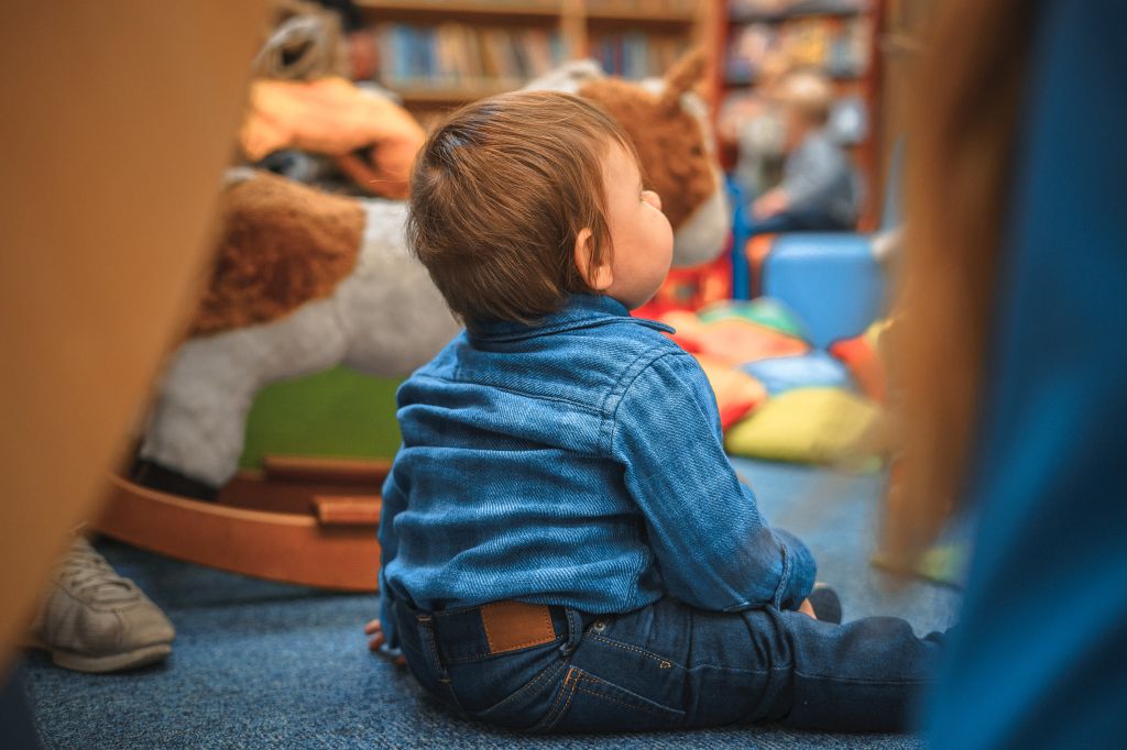 Baby Boy Sitting On Floor At Nursery