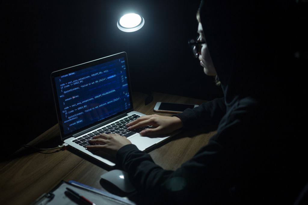 Young hooded woman hacker doing cyber attack