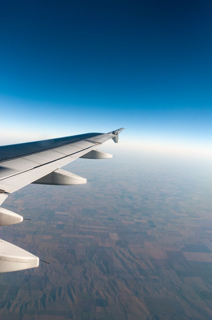 View of wing of a Frontier Airlines commercial jet airplane flying over the Northwest