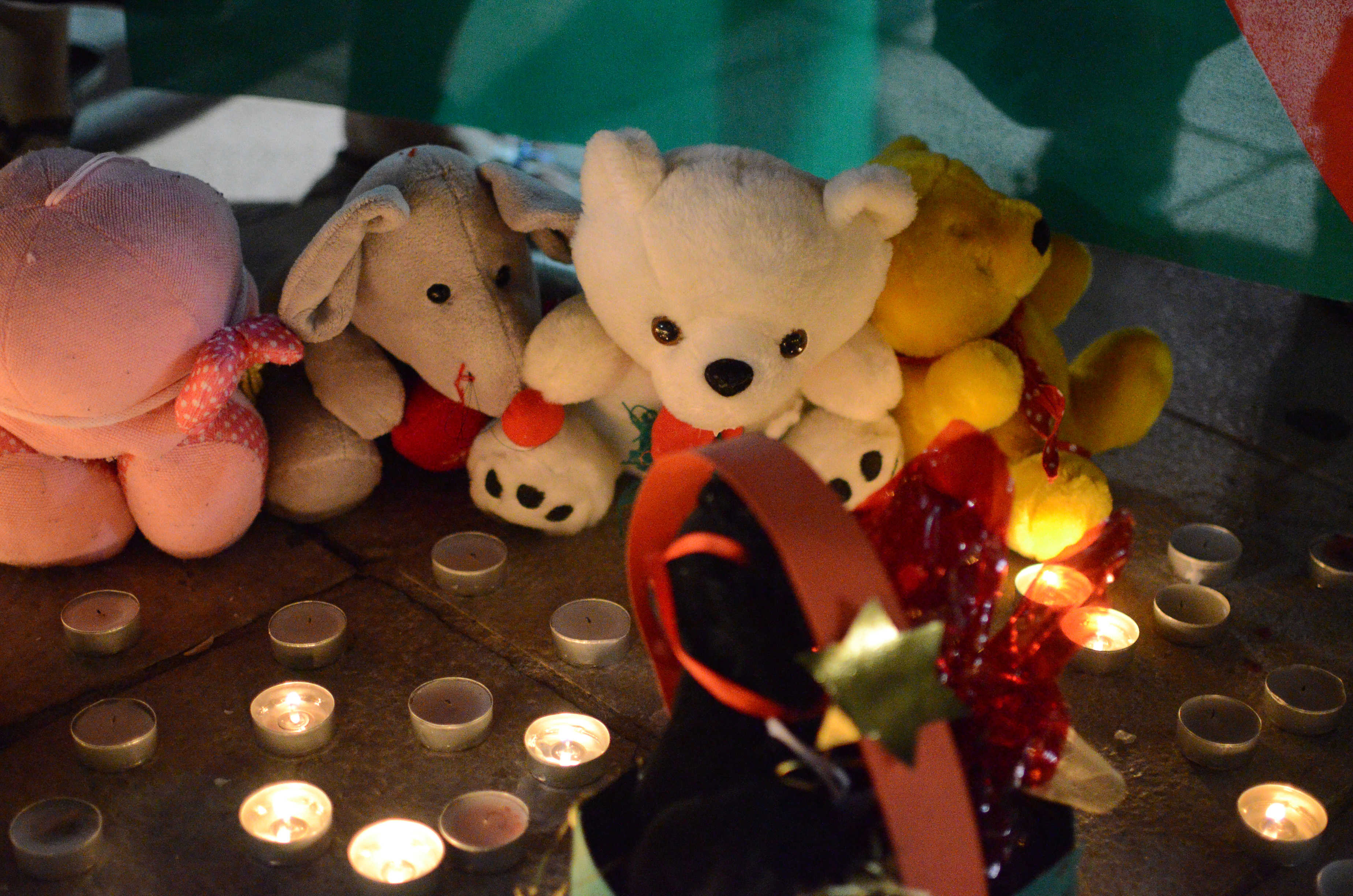 People leave assorted toys and candles in the memory of the...