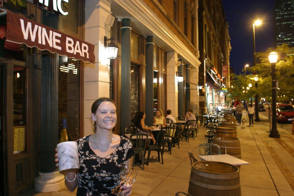 A woman holding a bottle of wine outside a wine bar in the Warehouse District.