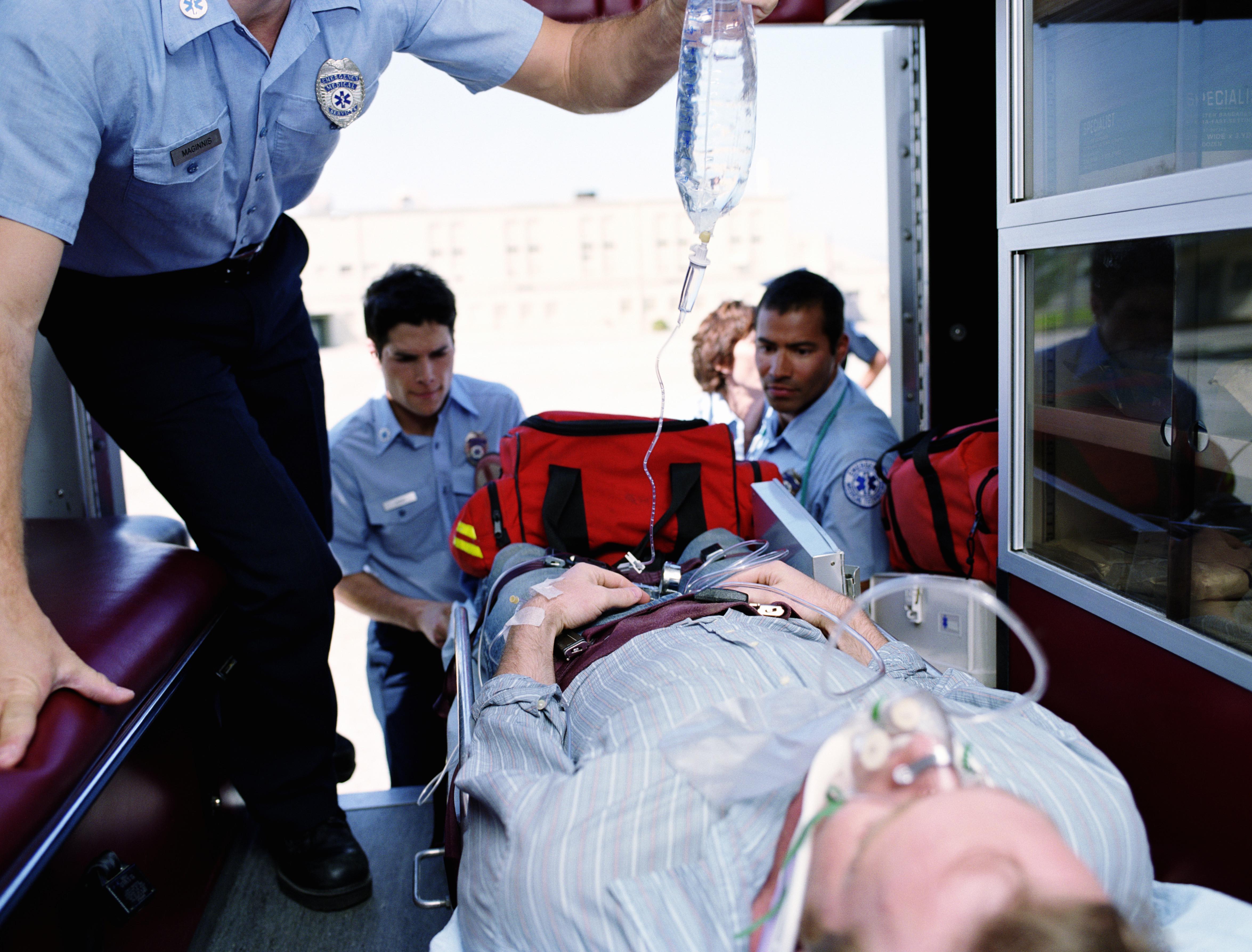 Emergency medical technicians putting patient on gurney in ambulance