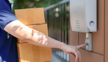 Delivery service courier ringing the house doorbell with boxes in hands