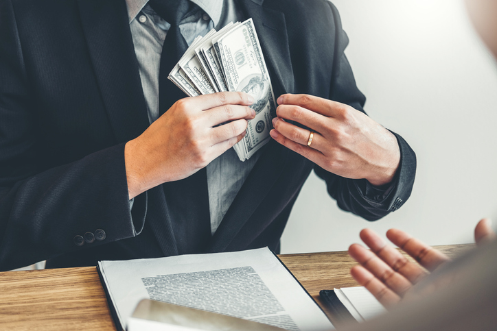 Midsection Of Agent Putting Paper Currency In Suit At Office