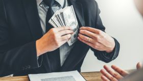 Midsection Of Agent Putting Paper Currency In Suit At Office
