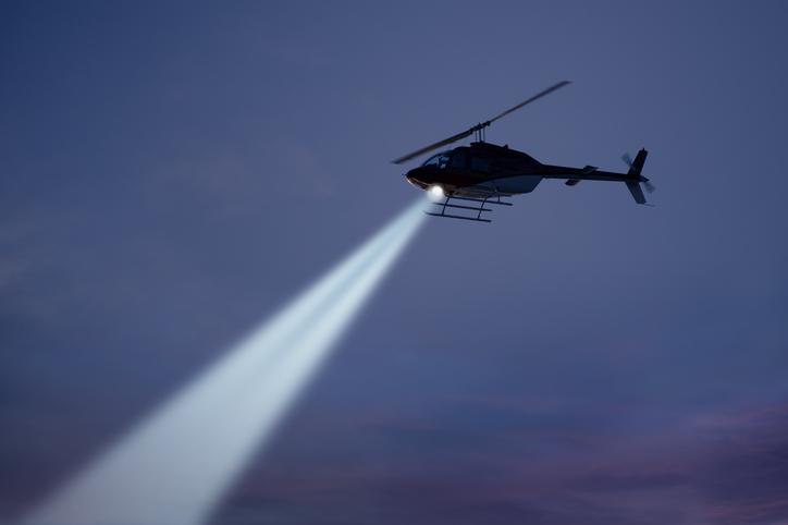 Police helicopter shining a light beam in the dark sky