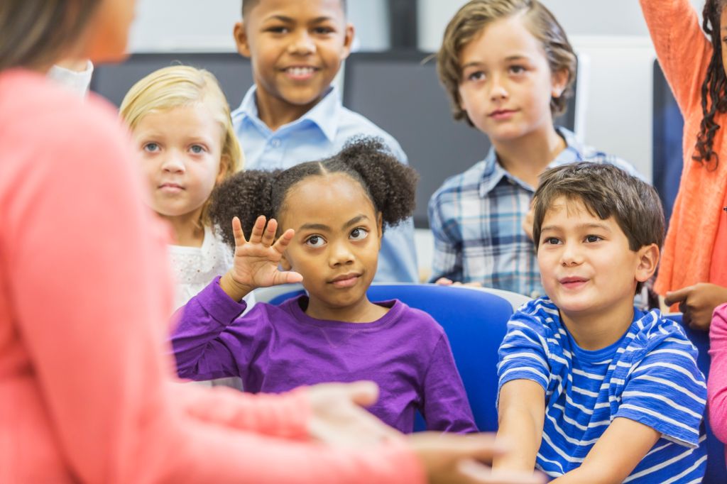 Multi-ethnic group of children, girl raising hand