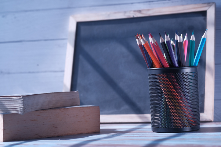 colorful pencils in a pencil pot, books and blackboard