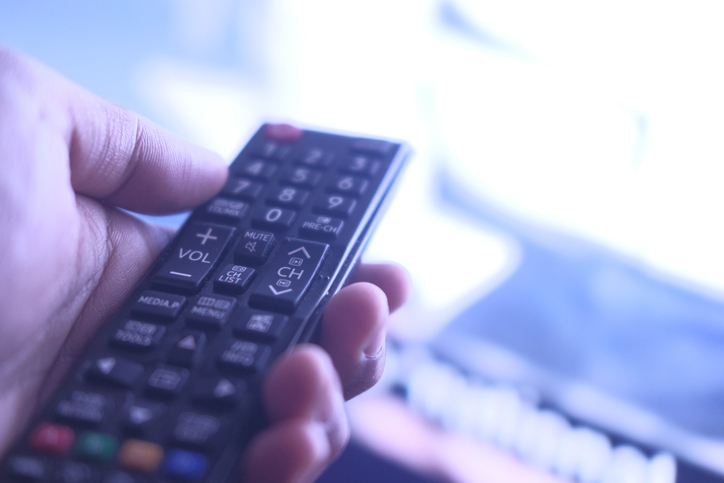Man hand with Tv remote watching tv