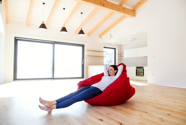 Young woman sitting on a bean bag in living room in a new home, resting.