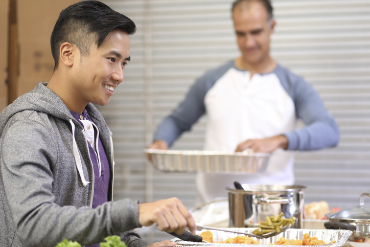 Multi-ethnic group of volunteers serves food at soup kitchen.