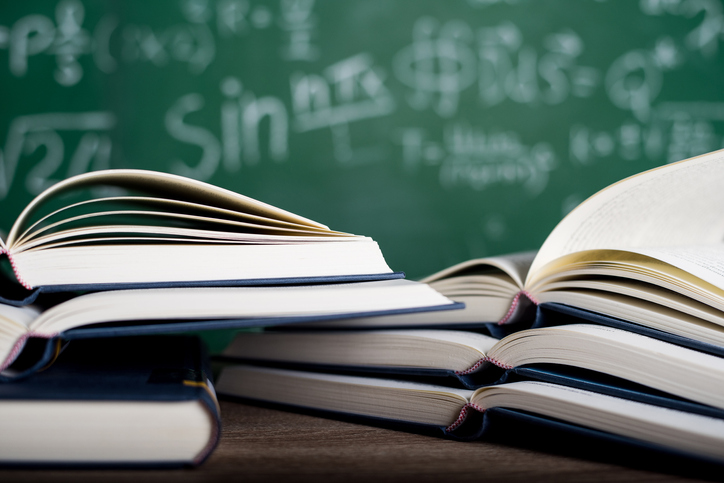 Close-Up Of Open Books On Desk In Classroom