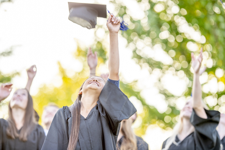 Graduating students throw their mortarboards in the air