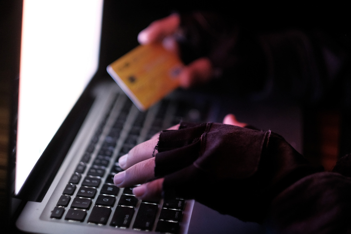 young hacker stealing credit card information from internet working on laptop