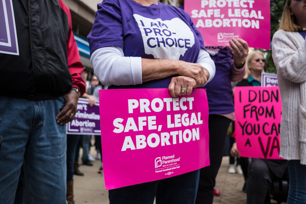 An activist seen holding a placard that says protect safe,...
