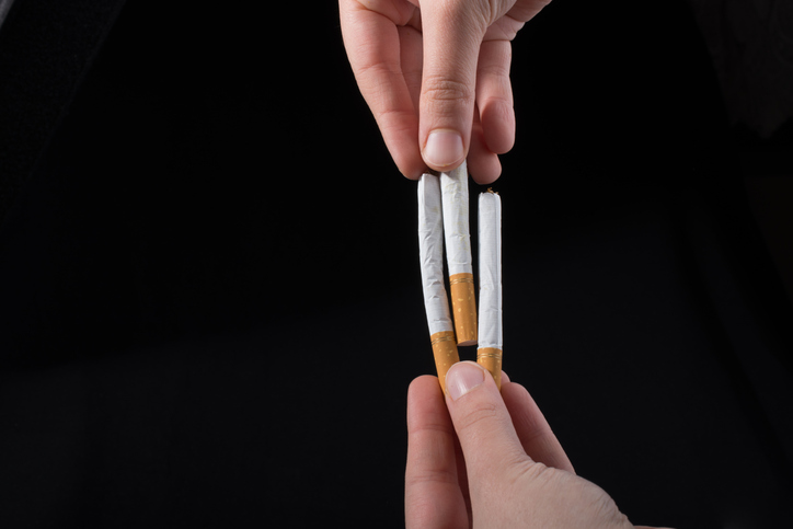 Cropped Hands Of Person Holding Cigarettes Against Black Background