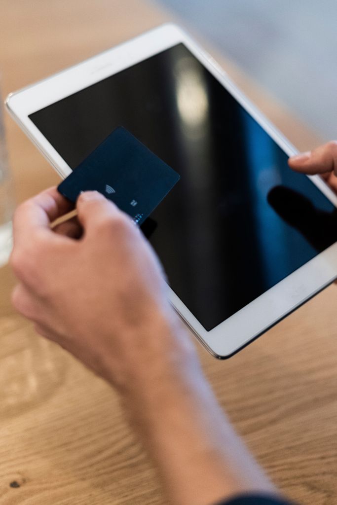 Close-up of man using tablet and holding credit card