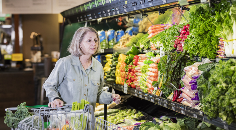 Senior woman shopping in produce aisle of grocery store