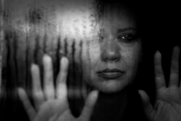 Depressed woman looking out of rainy window