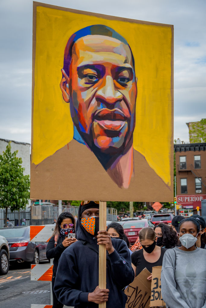 A participant holding a George Floyd's painted portrait at...