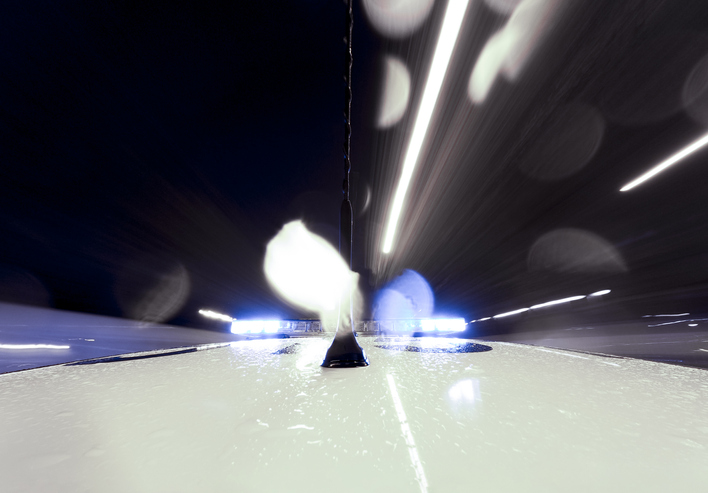 Onboard camera in police vehicle with sirens on rainy day.