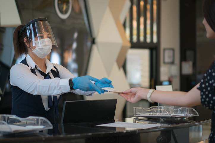 Receptionist lady welcomes her customer with protective face mask