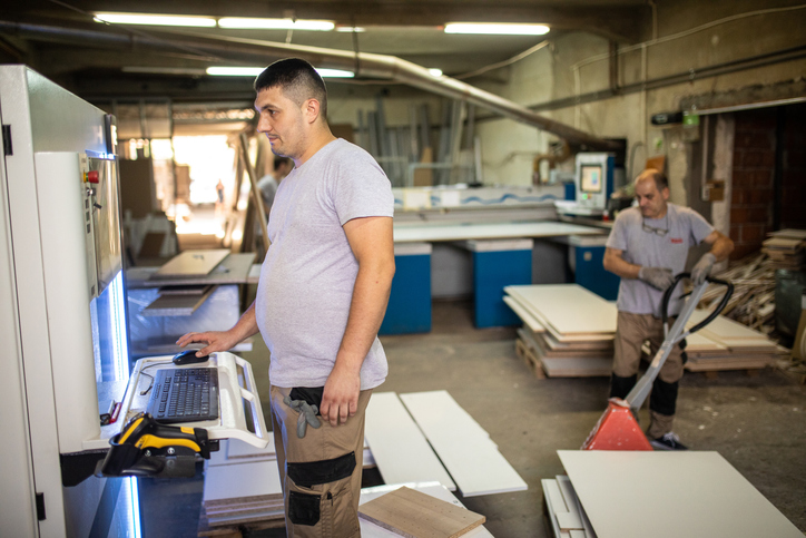 Manual worker operating CNC machine in woodworking company