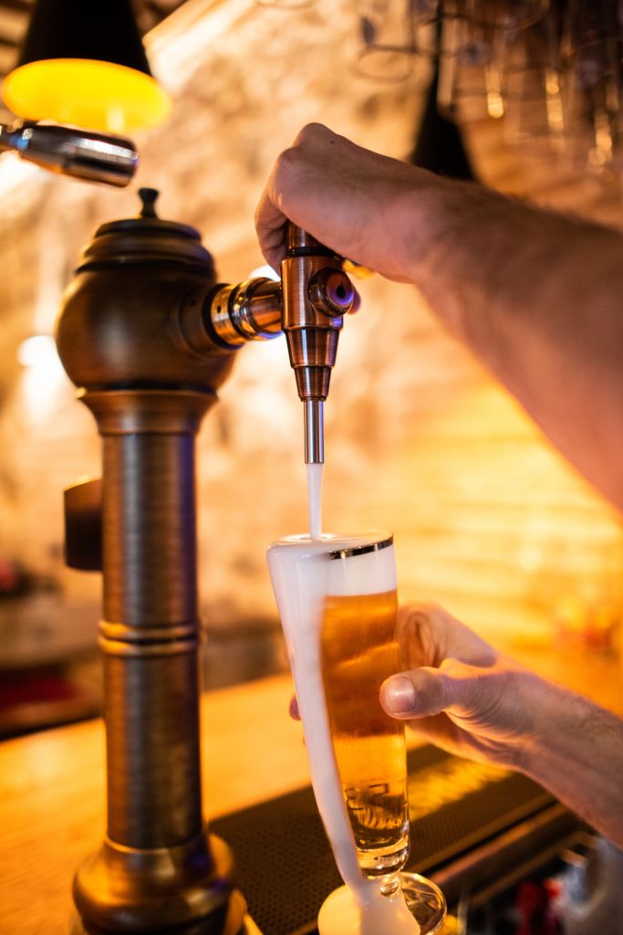 Waiter pulling a mug of beer from tap with foam