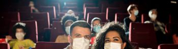 Happy couple wearing face masks and enjoying the movie at the cinema