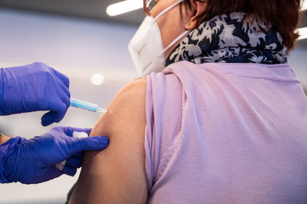 A nurse vaccinating a woman with the first dose of...