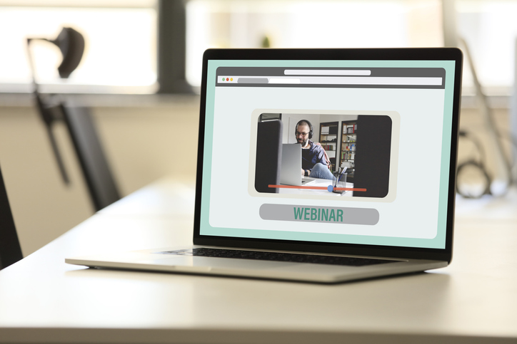 Laptop with webinar screen on wooden desk