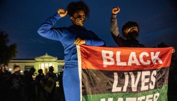 Protesters wearing facemasks stand with a Black Lives Matter...